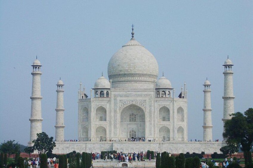 The Taj Mahal with four minarets, a large central dome, and a crowd of people in the foreground. 5