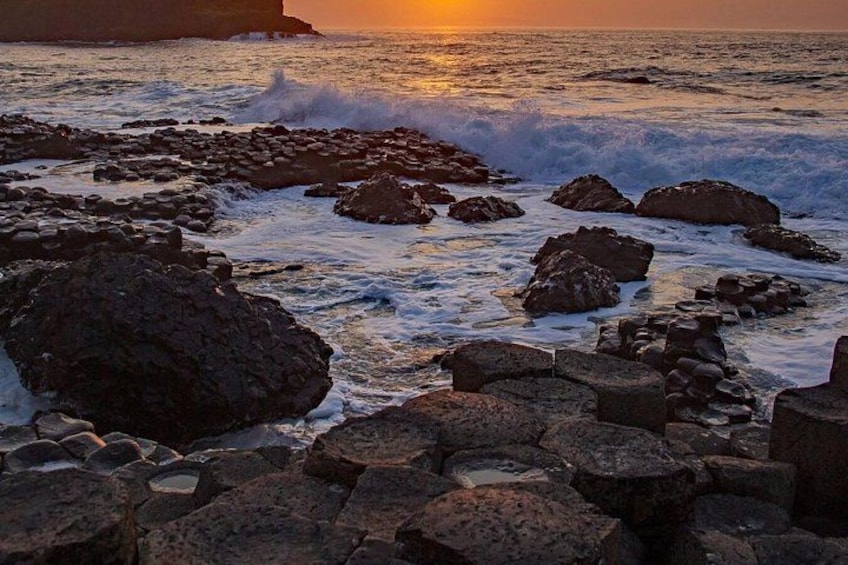 A rocky shoreline with waves crashing against the rocks during sunset. 4