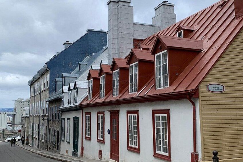 Une rue bordée de bâtiments historiques, de maisons aux toits rouges et d’une enseigne indiquant « Hôtel ». 4