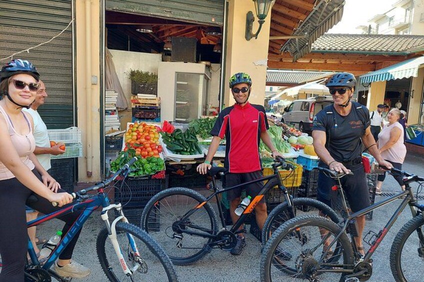 Folk med cykler foran en bod med frisk frugt og grønt. 2