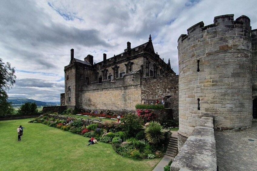 A historic castle with a well-maintained garden and a large stone tower. 3