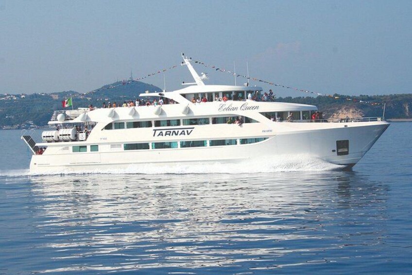 A white boat named 'TARNAV' with 'Estrella Queen' written on the side, sailing on water with a hilly landscape in the background. 1