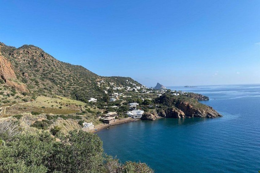 A coastal landscape with a small settlement, a mountain, and the sea. 4