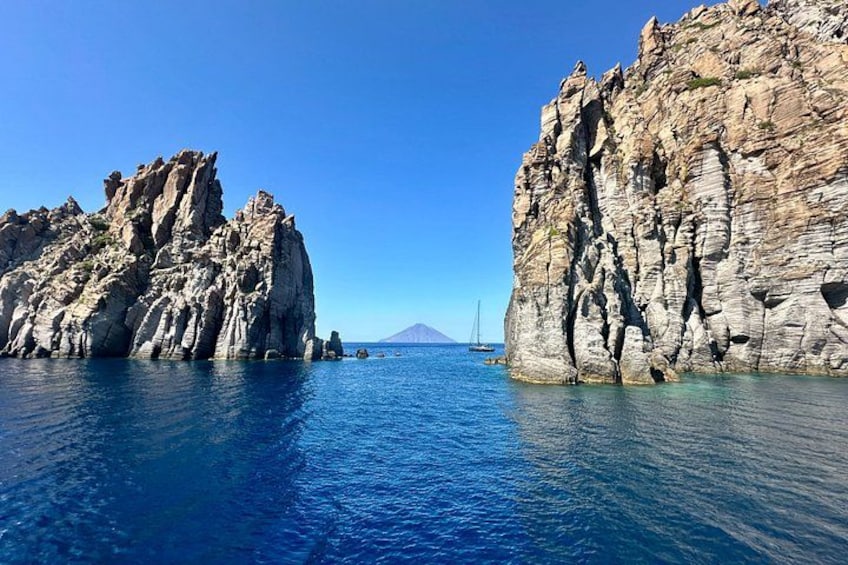 A rocky coastline with clear blue water and a distant mountain. 2