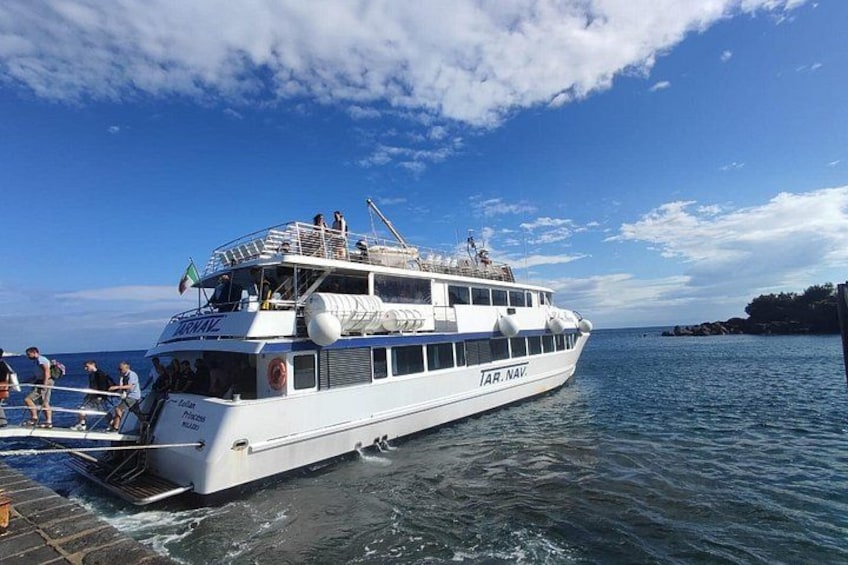 A white boat with 'JAR. NAV' written on the side, docked at a pier with people boarding and disembarking. 3