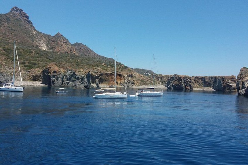 A coastal scene with boats anchored near rocky cliffs under a clear sky. 2