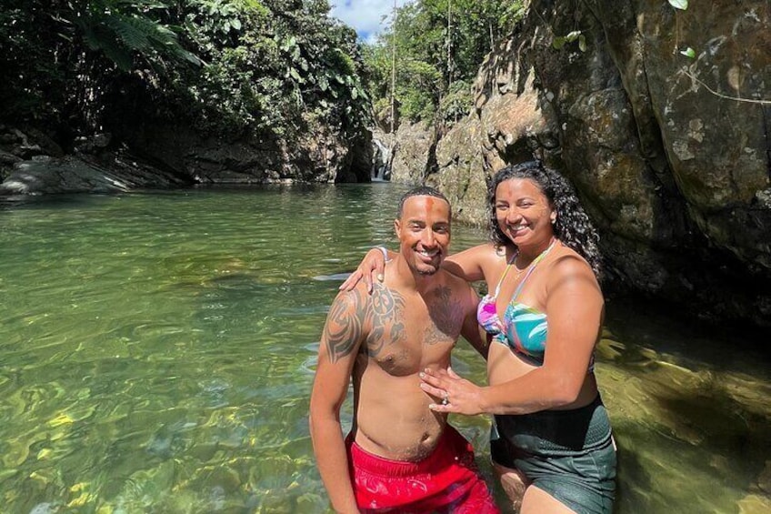 Two people standing in clear water with a rocky background. 2