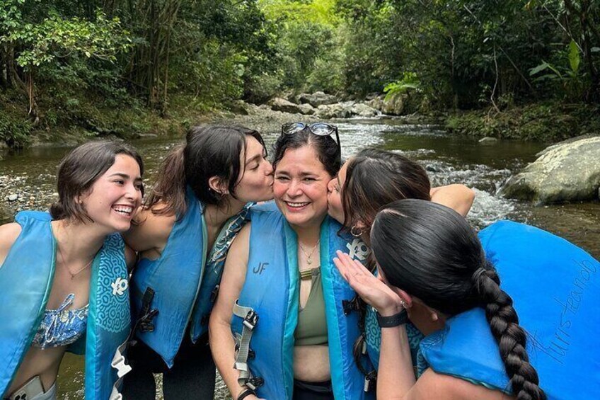 A group of people wearing blue life jackets by a river surrounded by greenery. 5