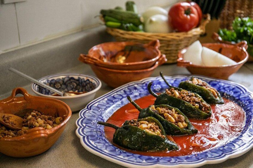 Pimientos rellenos en un plato, rodeados de varios boles y utensilios de cocina. 2