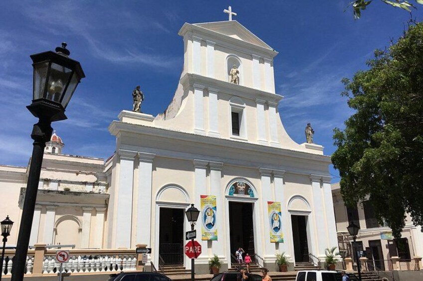 A white church with a bell tower, a street lamp, and a 'PARE' sign. 2