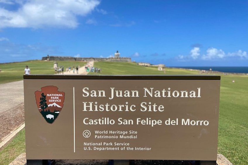 A sign for the San Juan National Historic Site with a coastal background. 3