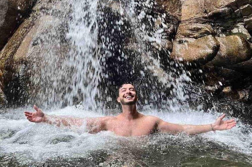 Eine Person in einer natürlichen Wasserlandschaft, im Hintergrund ein Wasserfall. 2
