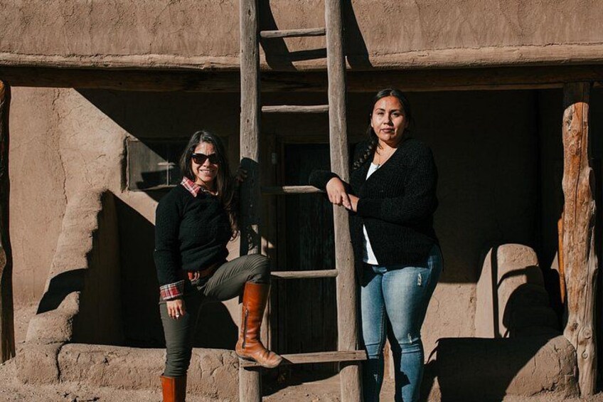 Two people standing near a wooden ladder and a stone wall. 3