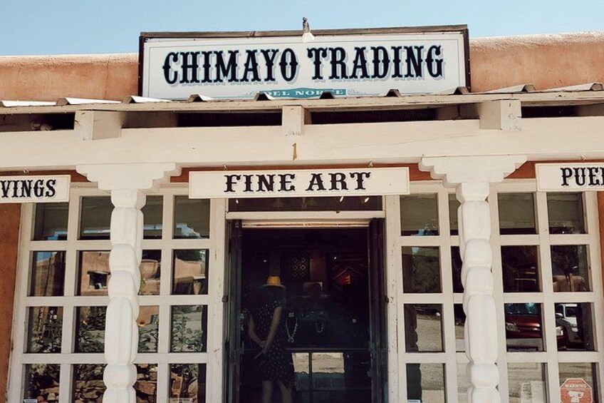 A building with a sign that reads 'CHIMAYO TRADING' and 'FINE ART' displayed above the entrance. 4