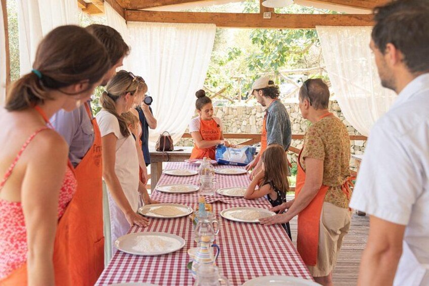 People gathered around tables with red and white checkered tablecloths, under a tented structure. 3