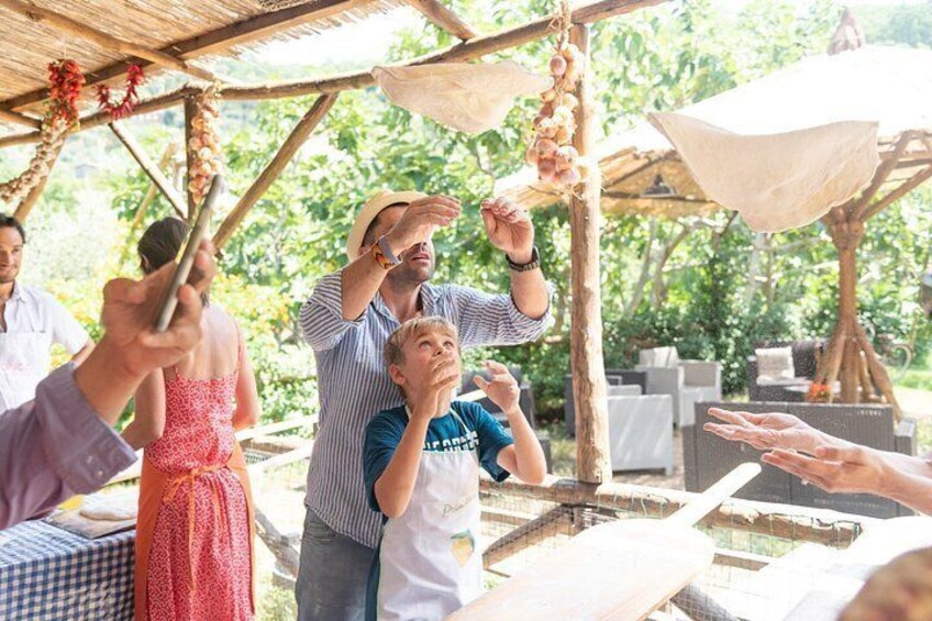 A group of people at an outdoor event with a wooden structure, tables, and hanging decorations. 1
