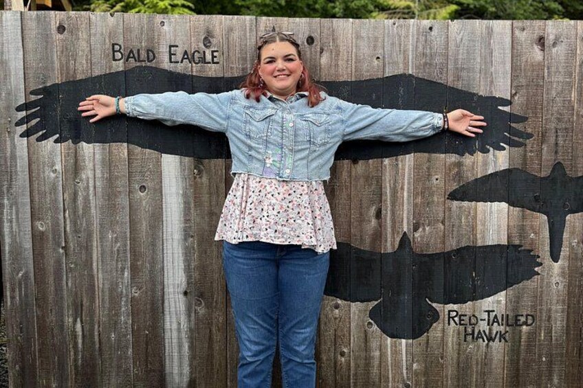 A person standing in front of a wooden fence with bird silhouettes and text. 3