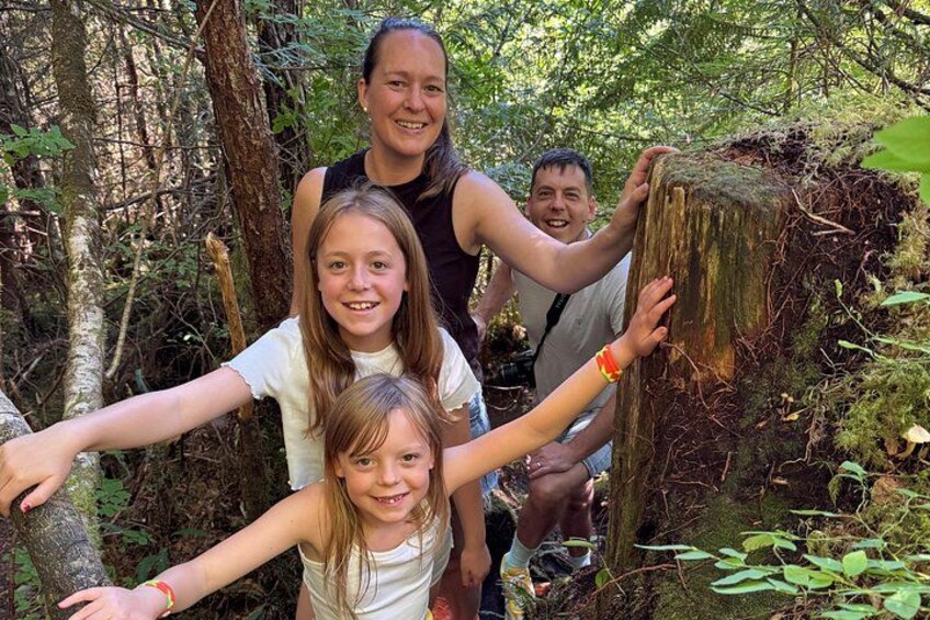 A group of people in a forested area with a large tree stump. 5