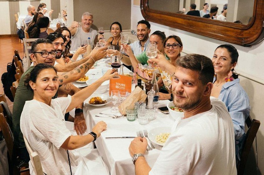 A group of people toasting at a dinner table with a sign that reads 'TOURS BECY.' 3