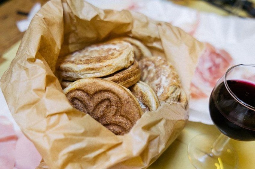 A basket of pastries and a glass of red wine. 4
