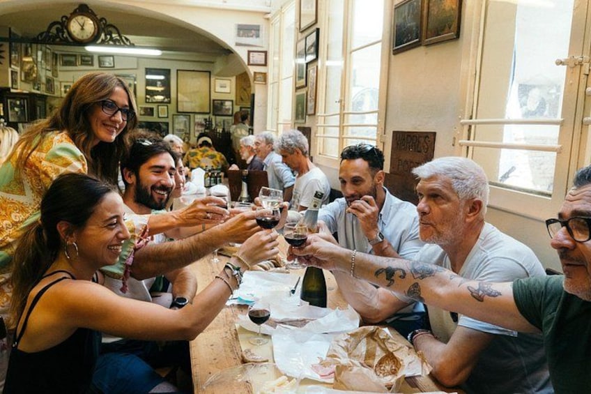 A group of people toasting with wine glasses at a table in a restaurant. 1