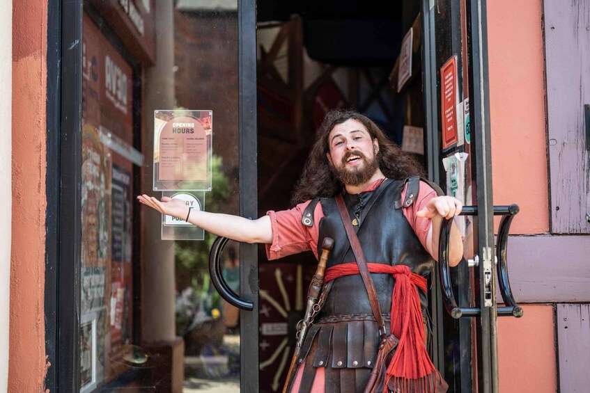 A person in medieval attire holding a sign with opening hours. 2