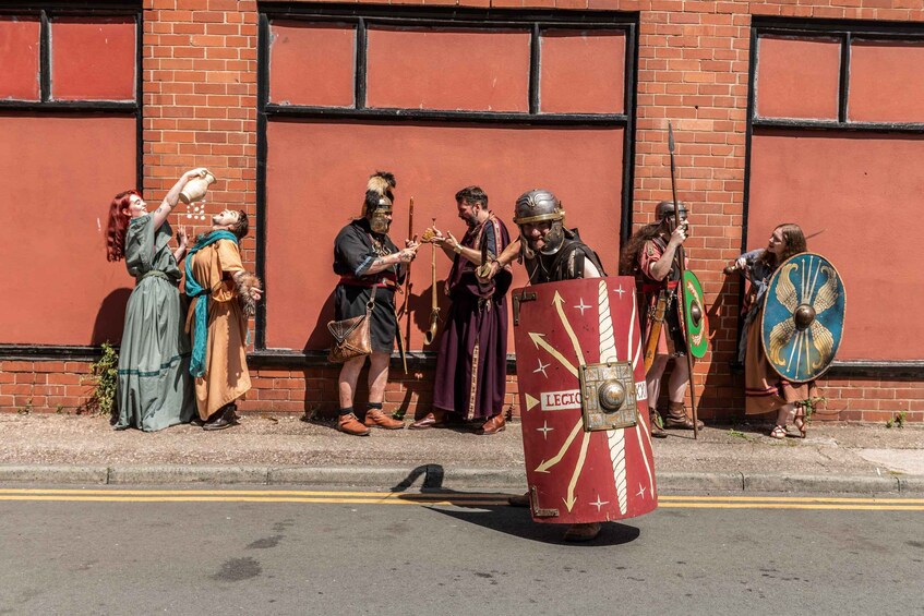 A group of people in historical costumes standing in front of a red brick building. 5