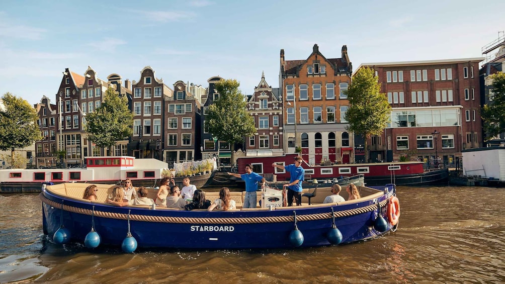 A blue boat named STABBOARD docked in a canal with people on board. 1