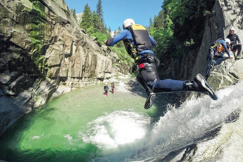 A person rappelling down a rocky cliff into a green body of water. 2