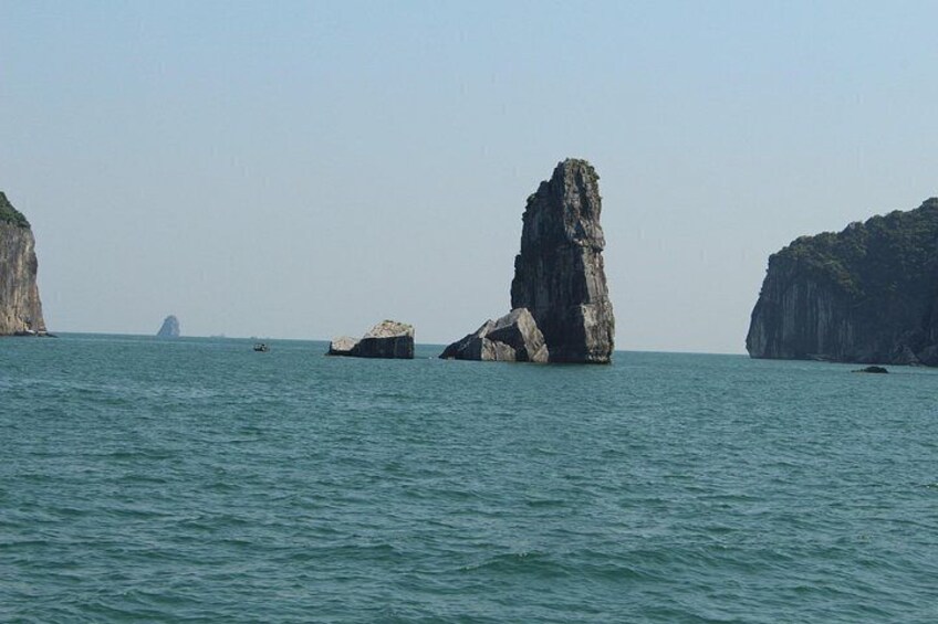 A calm sea with large rock formations and a distant island. 3
