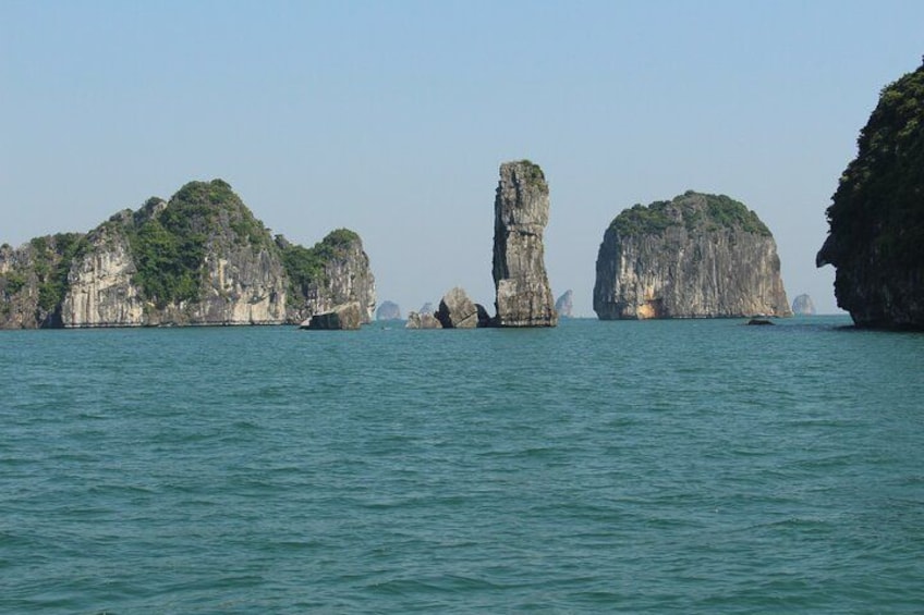 A coastal landscape with prominent limestone karsts and calm sea. 4
