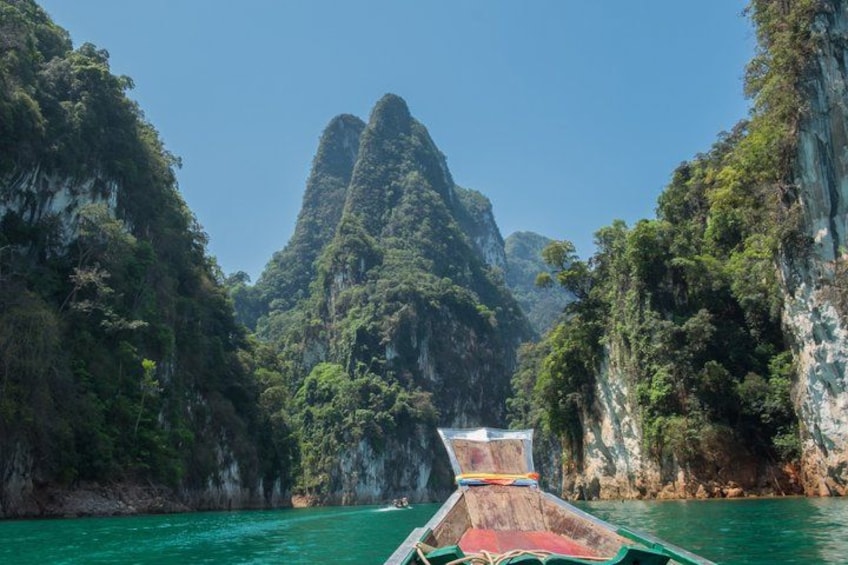 Un bote en un río turquesa rodeado de acantilados escarpados y cubiertos de bosque. 3