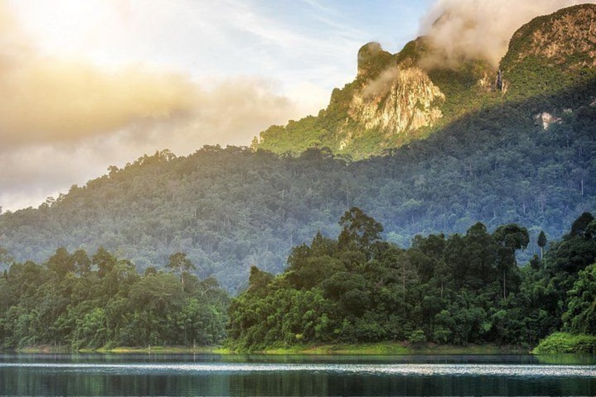 A mountainous landscape with a lake, dense forest, and a misty peak. 2