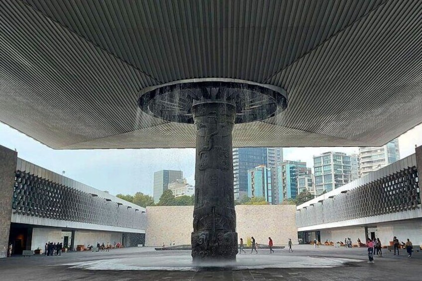 A modern architectural structure with a central column and a patterned ceiling. 1