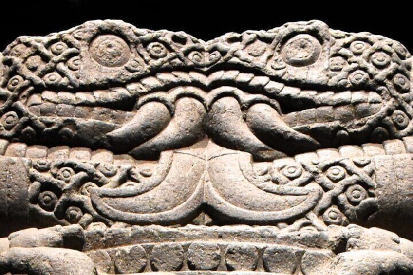 A detailed stone carving of a mythical creature with intricate patterns and a prominent eye. 3