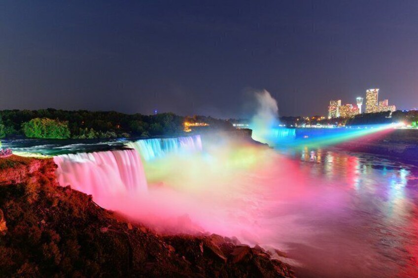 A waterfall at night with colorful lights reflecting on the water. 2