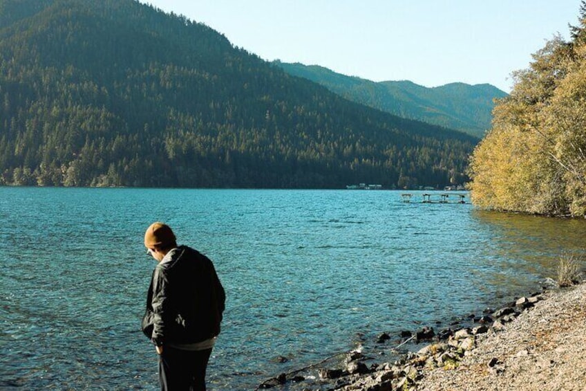 A person standing by a lake with mountains in the background. 4