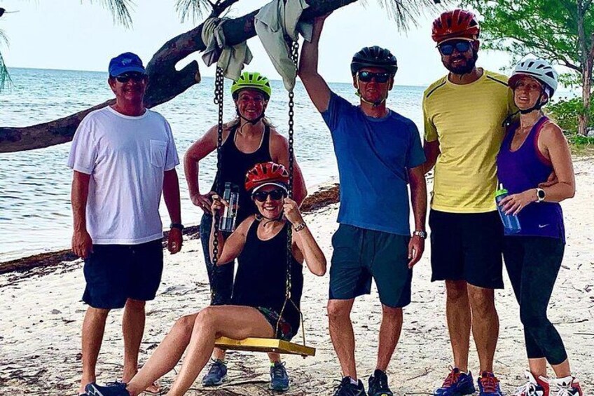 Un grupo de personas en una playa, con una hamaca y un bote al fondo. 2