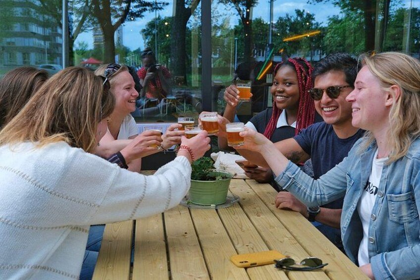 Een groep mensen proost met drankjes aan een houten tafel buiten. 4