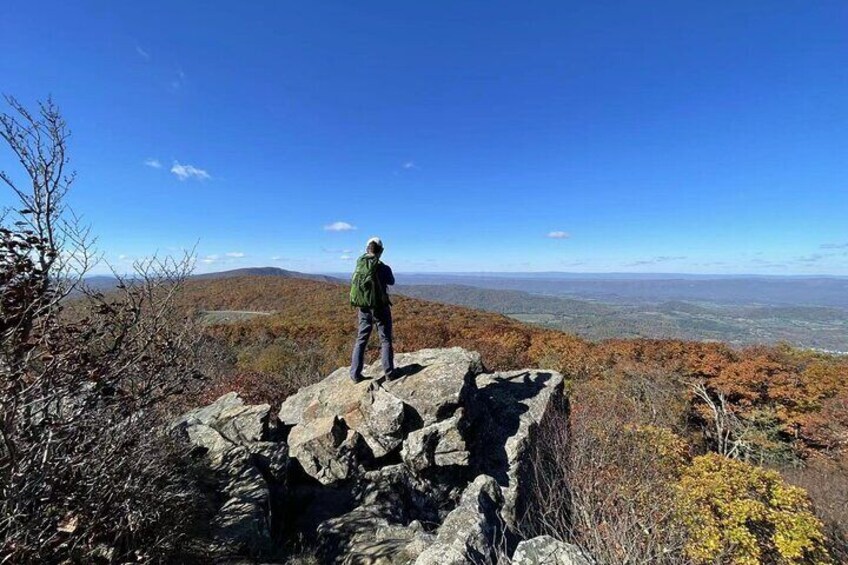A person standing on a rocky outcrop overlooking a mountainous landscape. 3