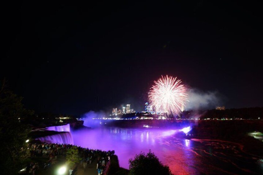 A nighttime fireworks display over a body of water with a city skyline in the background. 3