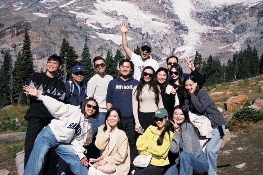A group of people posing in a mountainous area with snow-capped peaks in the background. 4