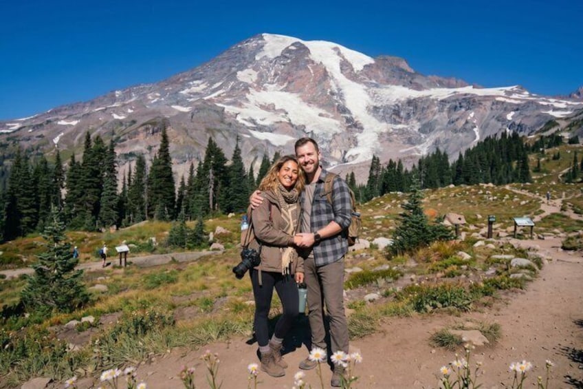 A couple standing in a mountainous area with a snow-capped peak in the background. 1