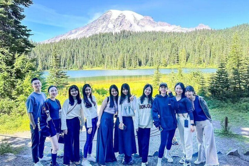 A group of people standing in front of a lake with a mountain in the background. 5