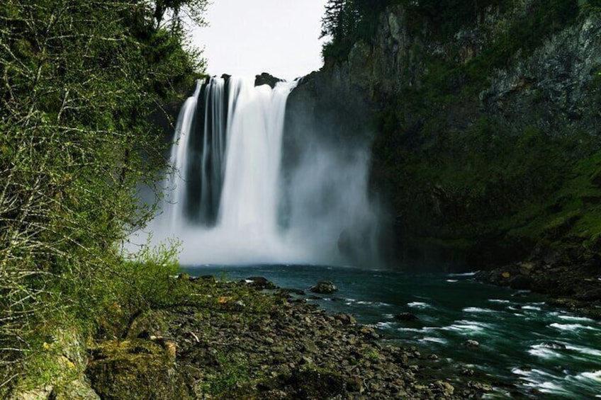 A waterfall cascading down a cliff into a river surrounded by lush greenery. 4