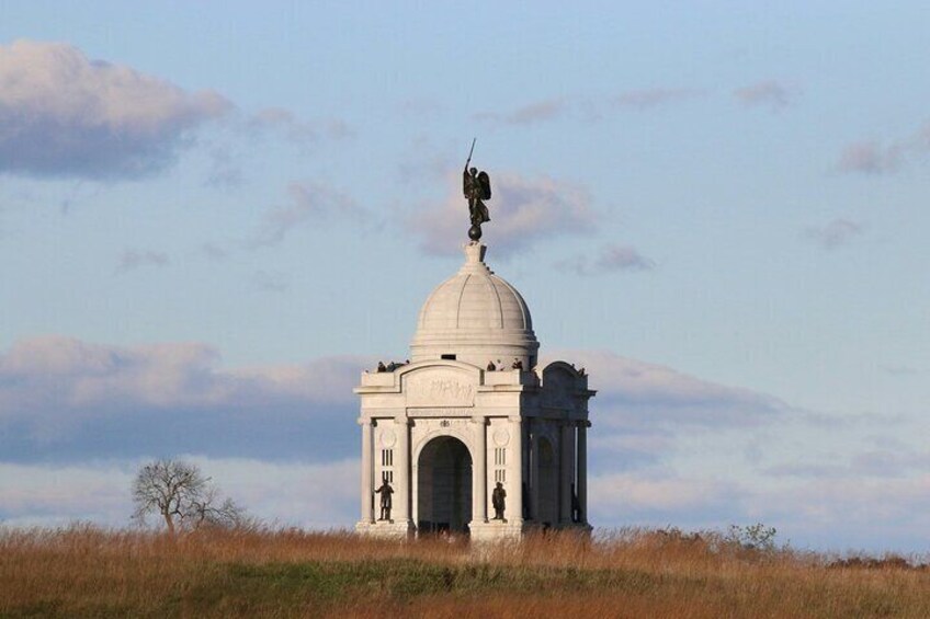 A white domed building with statues and a statue of an angel on top. 5