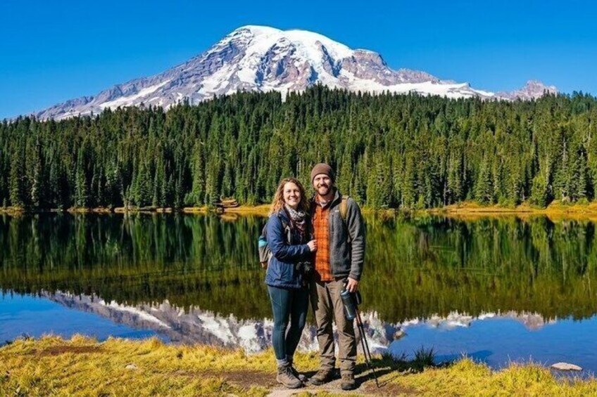 A couple standing by a lake with a mountain in the background. 4