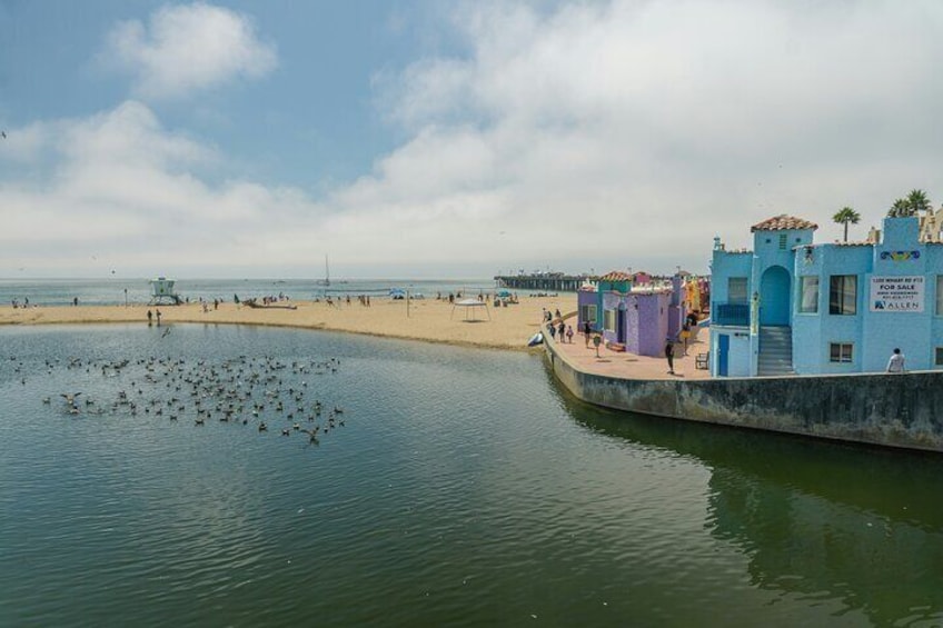 A coastal town with a beach, a pier, and colorful buildings. 3