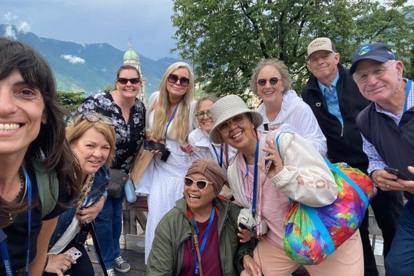 A group of people outdoors, some wearing hats, with a mountainous landscape in the background. 2
