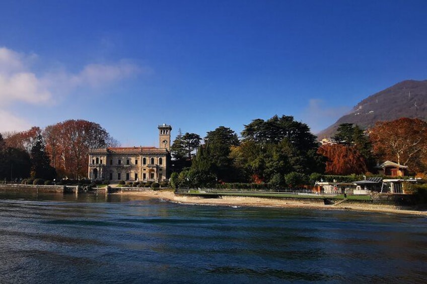 A historic building with a tower, a body of water, and autumn trees. 3